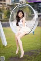 A woman sitting in a bubble chair in a park.