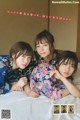 A group of three young women laying on top of a bed.