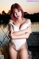 A woman in a white bathing suit posing on a dock.