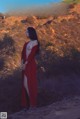 A woman in a red dress standing in front of the Hollywood sign.