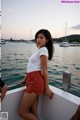 A woman in a white shirt and red shorts standing on a boat.