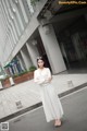 A woman in a white dress standing on the street.