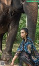 A woman sitting on the ground next to an elephant.