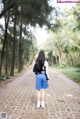 A woman walking down a brick path in a park.