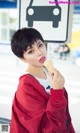 A woman in a red jacket eating an ice cream cone.