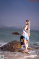 A woman standing on a rock in the ocean.