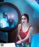 A woman in a red dress sitting at a desk with a laptop.