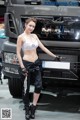 A woman standing in front of a truck at a car show.