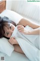 A woman laying in bed under a white sheet.