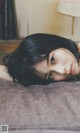 A woman laying on top of a couch next to a lamp.