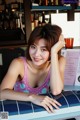 A woman sitting at a table in front of a bar.