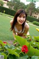 A woman in a white bikini posing in a garden.