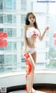 A woman in a red and white polka dot bikini posing by a window.