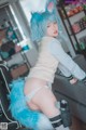 A woman with blue hair and a furry tail is posing for a picture.