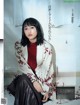 A woman sitting on the floor in front of a white brick wall.