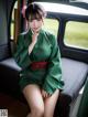 A woman in a green kimono sitting on a train.