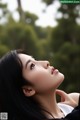 A woman with long black hair looking up at the sky.