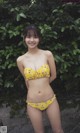 A woman in a yellow bikini posing for a picture.